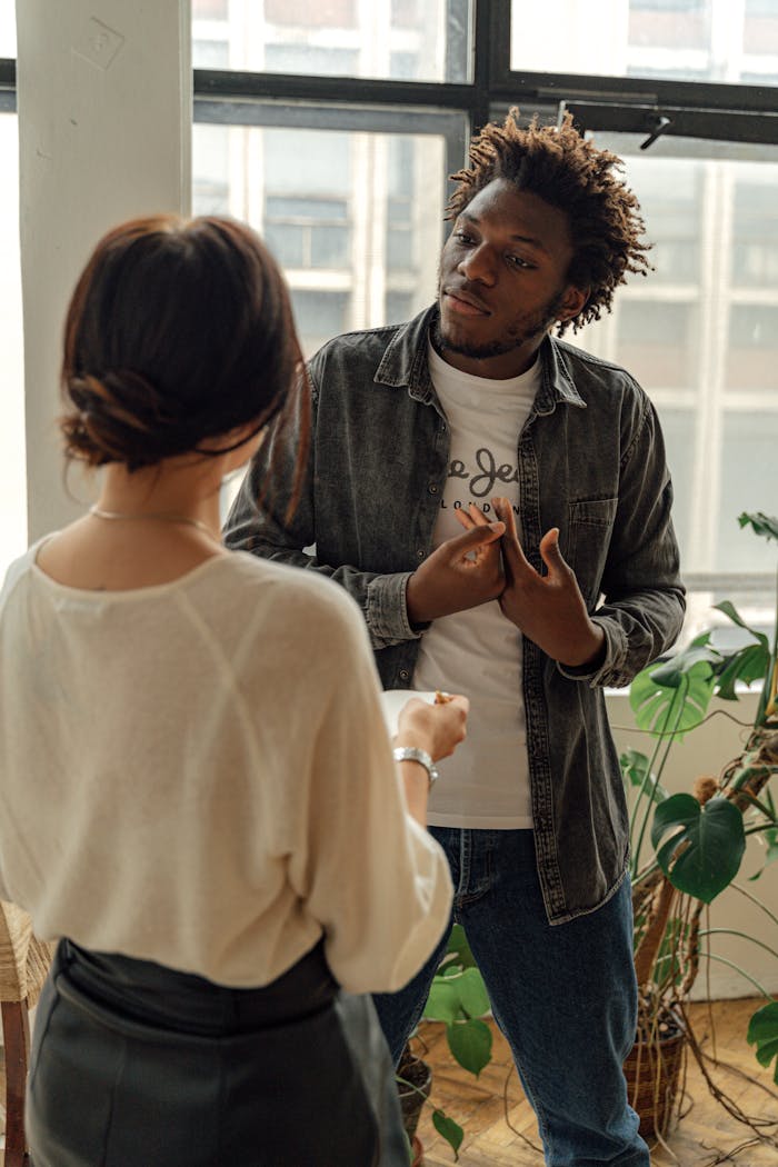 our-story Two adults engage in a casual conversation in a bright, modern office environment.