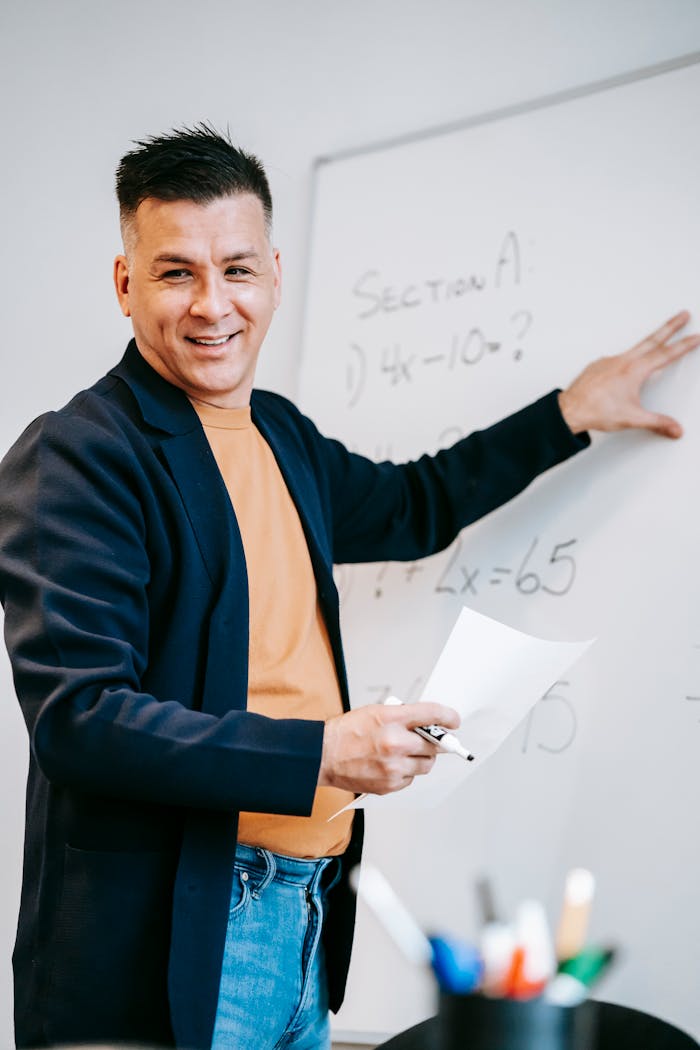 who-we-are Friendly teacher explains equations on a whiteboard in a classroom setting.